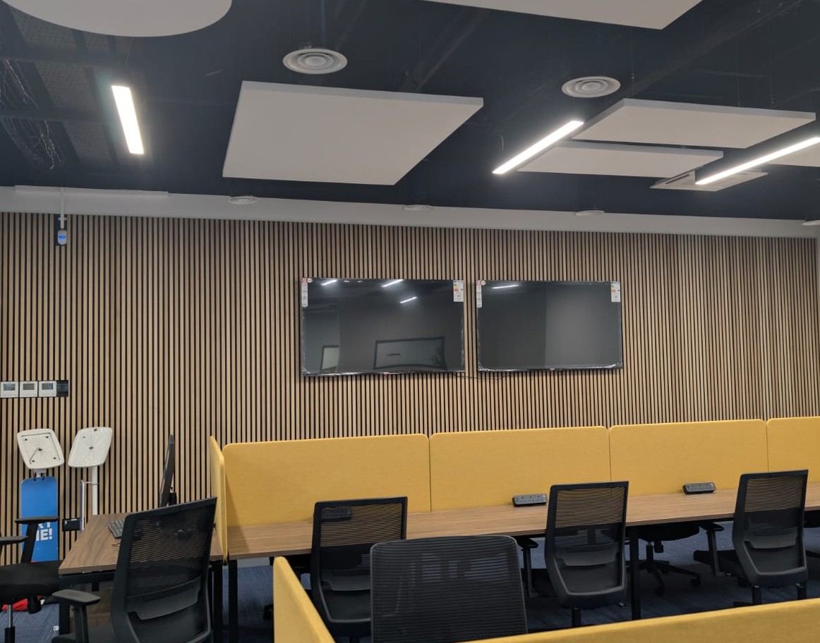 Two commercial displays flush-mounted on acoustic wall panels in open plan office for system monitoring